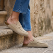 Womens suede clogs resting on a stone step with cropped jeans