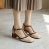 T strap square toe heels for women worn with tights and a pleated midi skirt on marble