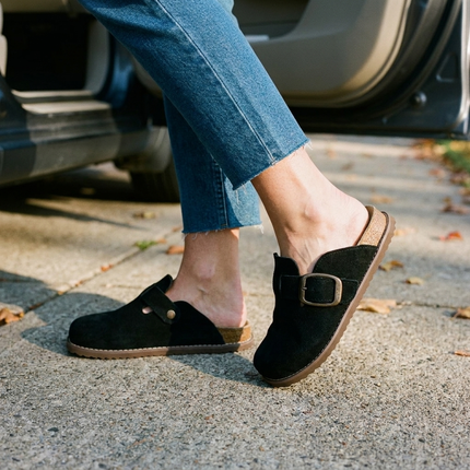 Women's suede clogs with cropped jeans beside an open car door on an autumn driveway