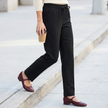Black pull on straight leg dress pants for women worn with burgundy Mary Jane flats on a sidewalk
