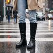 Knee high buckle riding boots for women in black with block heel, worn with jeans