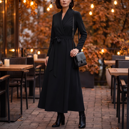 Woman wearing a black A-line wrap maxi dress with belt on an evening terrace