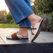Suede slippers for women in white with gold buckle on a patio