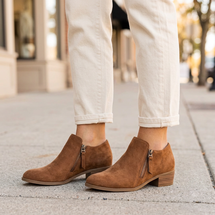 Women's suede ankle boots with side zip and low heel on a city sidewalk